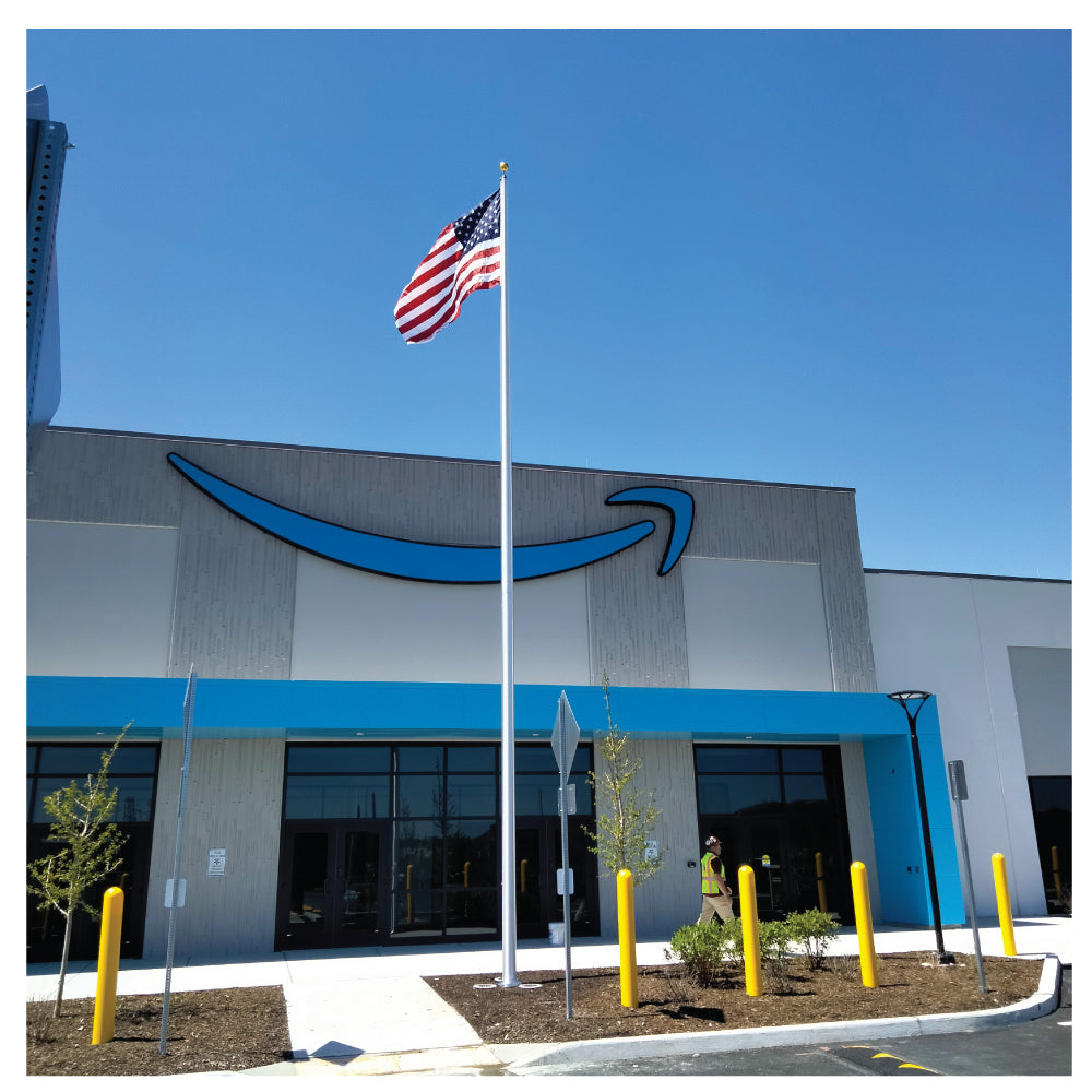 American flag on a pole waving in the sky in front of an Amazon store